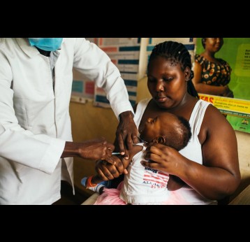 A mother brings her daughter to Ring Road Clinic, inside the Nyalenda B slum in western Kenya, for the second of four malaria vaccine shots. Credit: Kang-Chun Cheng