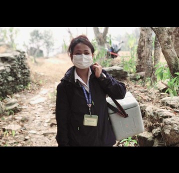 Kabita Chaudhari, senior health worker from Dhola Health Post in Jwalamukhi Rural Municipality, Dhading, on her way to the vaccination booth, carrying her ice-packed vaccine carrier. Credit : Chhatra Karki