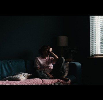 Femme assise dans une pièce sombre, avec un air fatigué. Crédit : Annie Spratt sur Unsplash