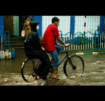 Two people riding a bike in a flooded city. Credit: Biplab Sau on Pexels