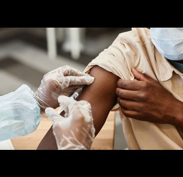 Close-up image of nurse in protective gloves giving patient injection of vaccine.