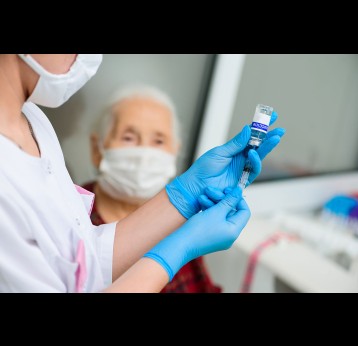 A nurse prepares to vaccinate an elderly woman.