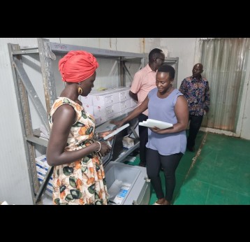 Cold Chain Assistant Supervisor, Lillian Juliie explains to Winnie about the ice packs. Credit: Denis Logonyi
