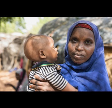A mother holding her child outside their home in Niger. Credit: Gavi/2022/Isaac Griberg