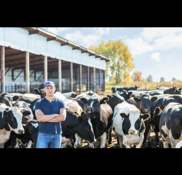 A dairy farmer with a herd of cows outside a farm. Credit: JENOCHE