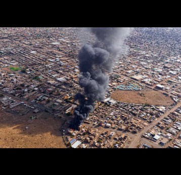 Smoke rises above a neighbourhood in the Sudanese city of Omdurman. Shutterstock/Abd Almohimen Sayed