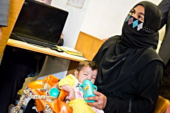 Nusarat, a young Pakistani mother, waiting to get her child vaccinated.