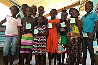 A group of girls show their vaccination cards during a HPV vaccination session in Liberia