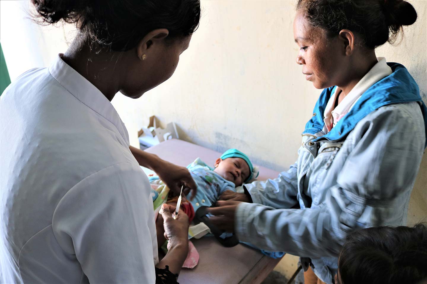 A health worker administers a vaccine to a baby as his mother watches on at the Comoro Community Health Centre in Dili. © UNICEF Timor-Leste/Galvin
