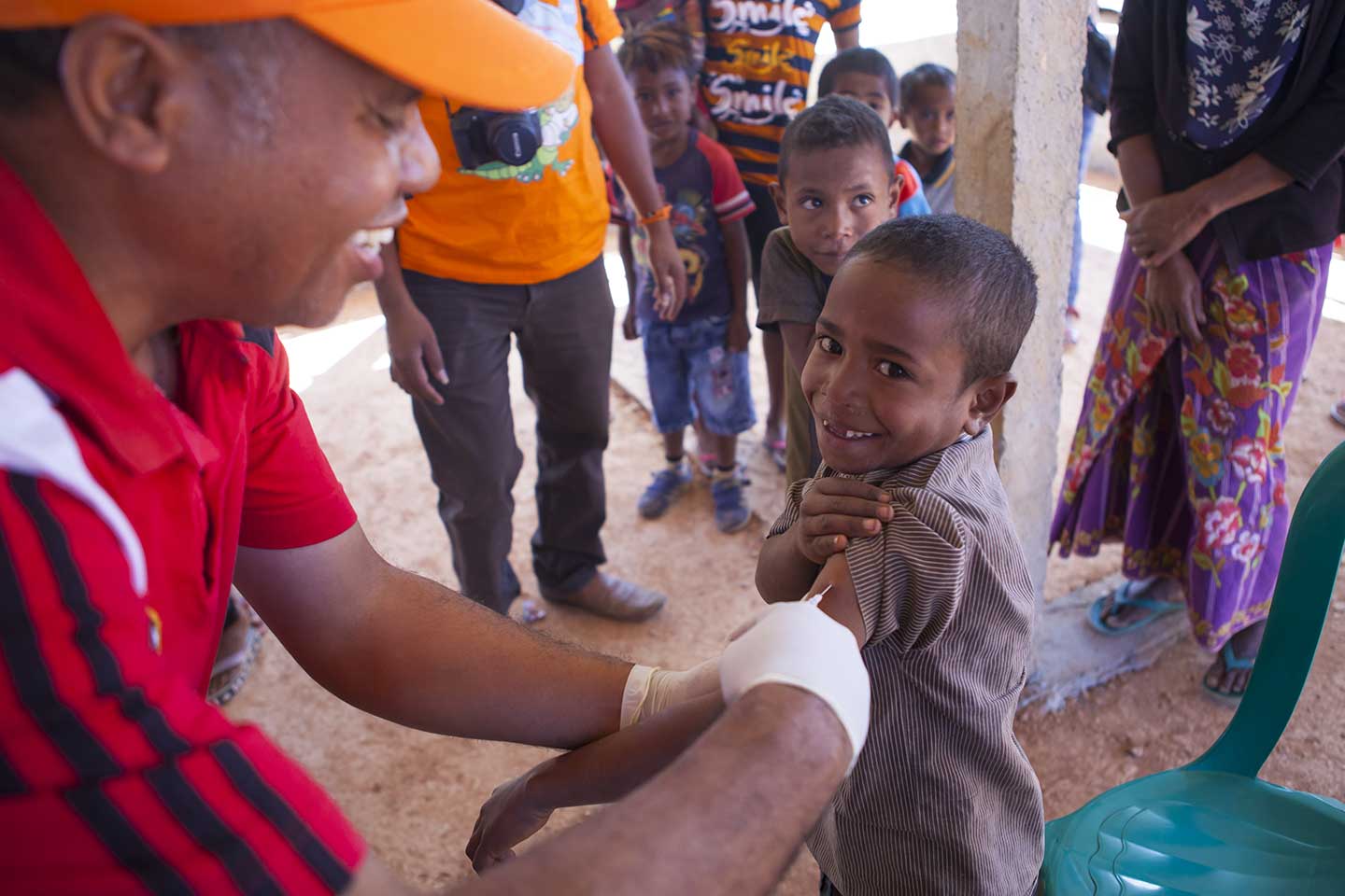 Young boy and a health worker are all smiles during a vaccination drive in Ermera Municipality. © UNICEF Timor-Leste/Soares.
