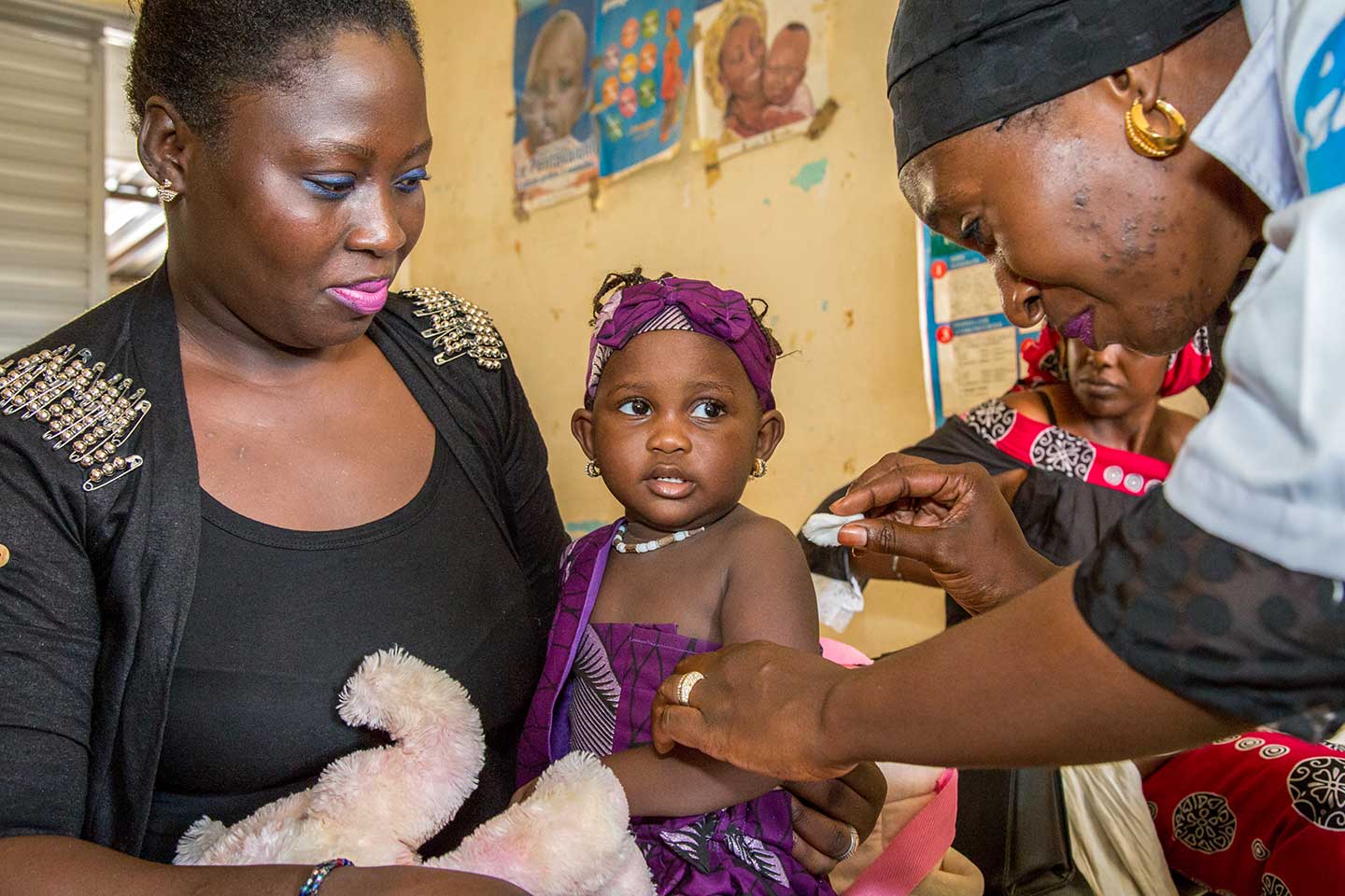 17 month-old Bilkhiss Diop has been brought in today by her mother, Oumou Hann (left), for the second dose of her measles-rubella vaccination. Gavi Special Envoy, Dagfinn Høybråten, joined the vaccination session in Louga district health centre, northern Senegal (September 2018). Mr Høybråten came to see how Senegal is managing to maintain high immunisation rates in more rural settings. Credit: Gavi/2018/Simon Davis