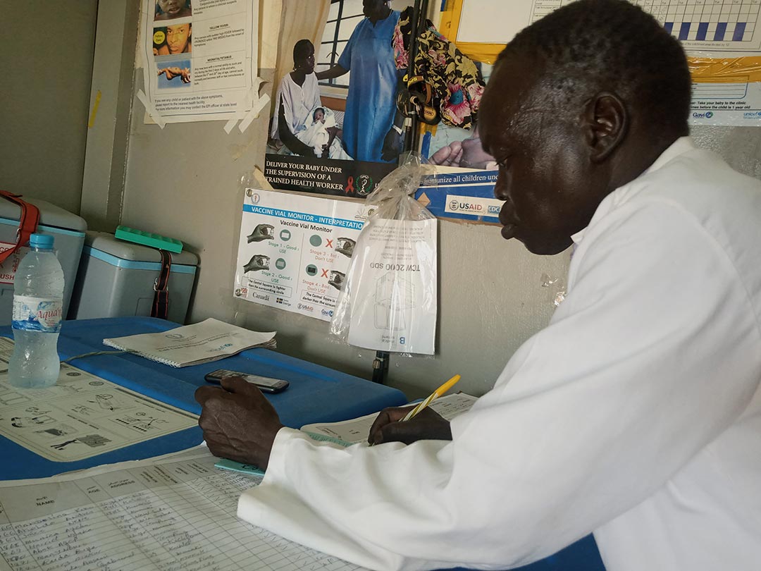 A health worker records details in a vaccination card. Credit: Winnie Cirino
