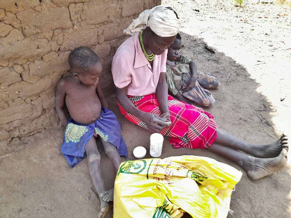 Ventorina Aculu sits next to her granddaughter (left) and youngest son (right). Aculu says that although they take medicine, her two sons with nodding syndrome, both now in their 20s, are not improving. Credit: Pat Robert Larubi