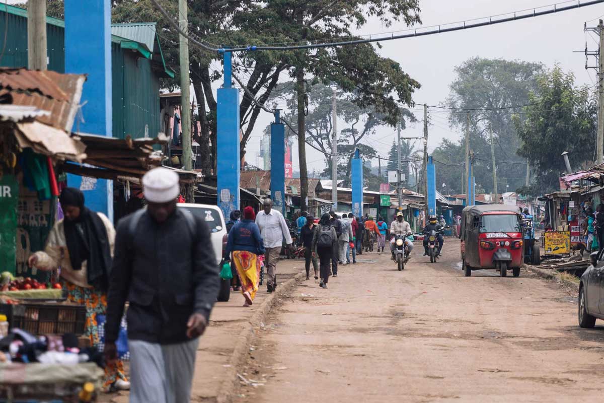 People in Kibera’s Makina section pass by the signature blue pillars that hold up SHOFCO’s aerial water piping system. Visual: Sarah Waiswa/Harvard Public Health Magazine