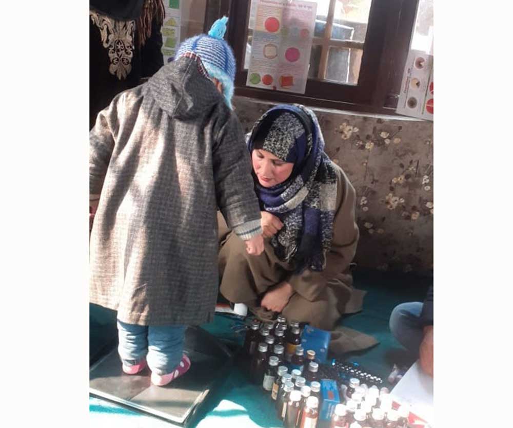 One of the routine jobs assigned to ASHA workers is a regular health checkup of mothers and children. Bilquis Ara, an ASHA worker, weighs a child in Kashmir.
