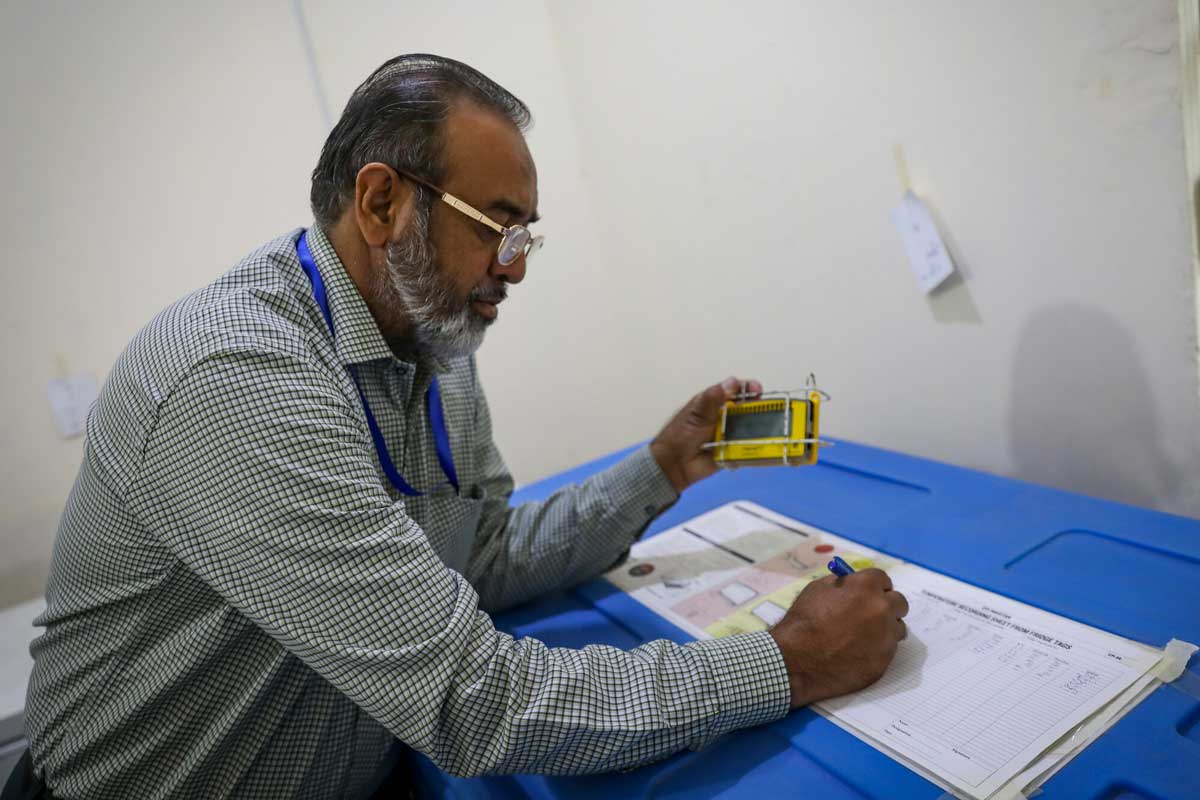 A government health officer reads data off a 30 Day Temperature Recorder - a device which can raise the alarm if a refrigerator's temperature should rise above or fall below the safe range for vaccine potency. Credit: Gavi/2023/Asad Zaidi