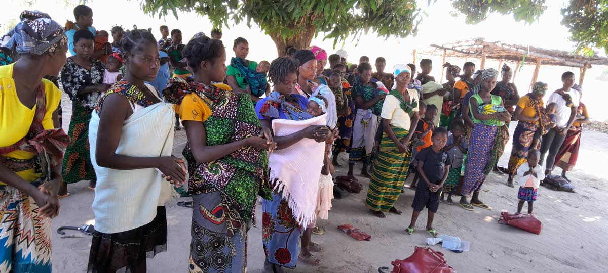 Mothers arrive and wait wait under a tree with their children for vaccinations. Credit: Charles Mangwiro.