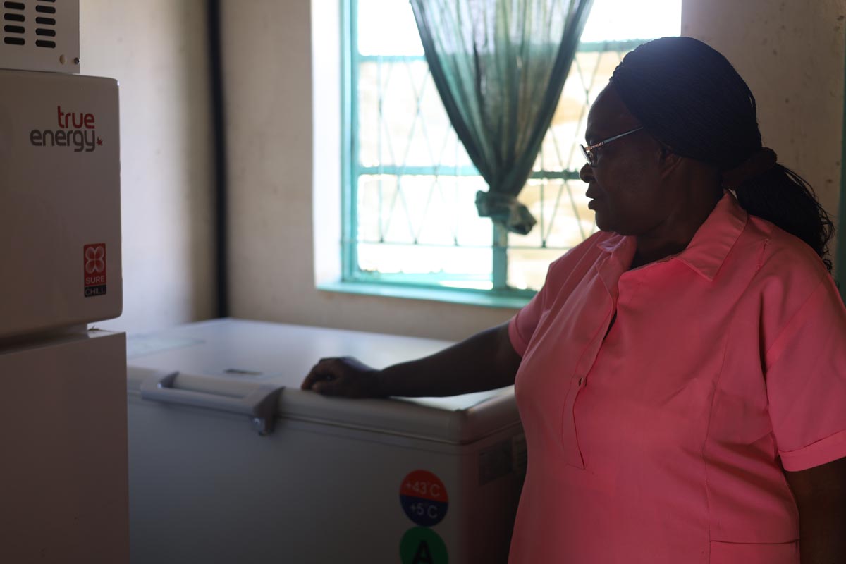 Tebitha Moyo, a nurse aide, looking at a fridge used to store vaccines at Hakwata Clinic, Chipinge. Credit: Farai Shawn Matiashe/2024/Gavi.