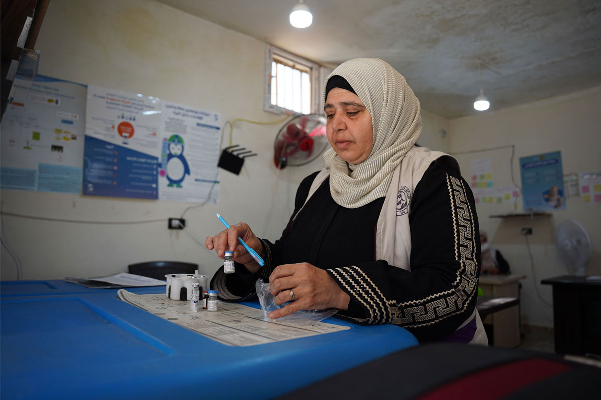 A health worker prepares vaccines before heading out to reach displaced families in Idlib. Credit: WHO