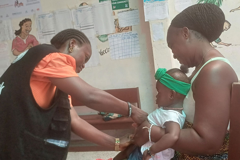 A vaccinator at the Star of the Sea injects Esther Sackie's daugther. Credit: Tina S. Mehnpaine