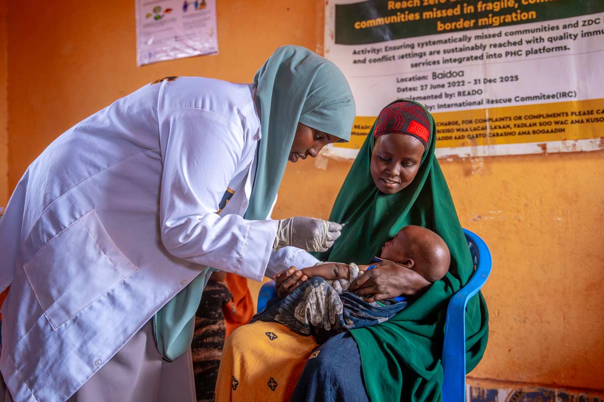 Un agent de santé administre un vaccin à un enfant tenu dans les bras de sa mère, dans le cadre de la campagne Reach Zero Dose Children (ZDC) en Somalie. Cette initiative vise à identifier les enfants n’ayant reçu aucun vaccin, ainsi que les communautés laissées à l’écart du système de santé. Crédit : Gavi/2024/Mohamed Abdihakim Ali